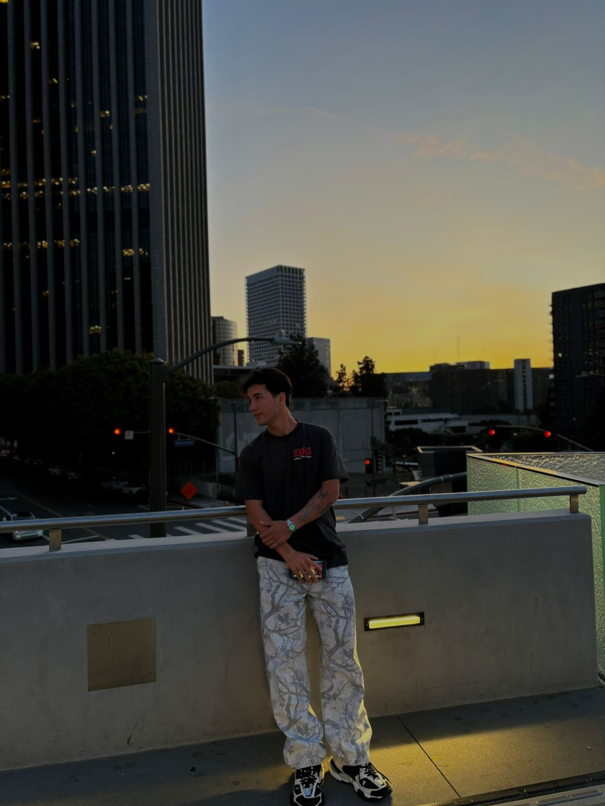 Alonso apoyado en una baranda con la ciudad al atardecer de fondo